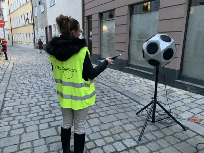 Pracovníčka AkuDesign na dláždenej ulici ovláda guľovú reproduktorovú sústavu na statíve