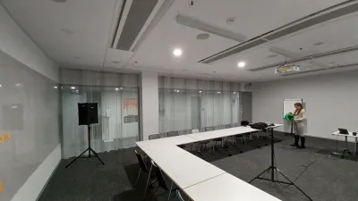 Reproduktor na statíve v modernej konferenčnej miestnosti so sklenenou priečkou počas merania
