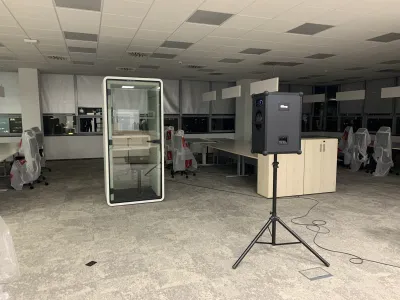Guľový reproduktor na statíve v rozostavanej kancelárii s telefónnou búdkou, nočné meranie.
