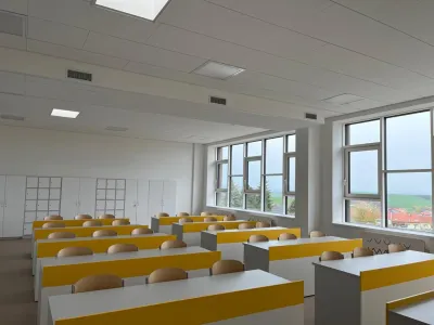 An empty classroom fitted with an acoustic ceiling and large windows.