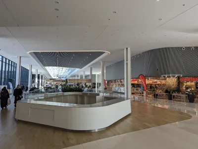 Shopping centre interior with a perforated acoustic ceiling above the central atrium.
