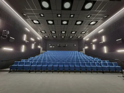 A cinema auditorium with blue seating and round acoustic ceiling panels.