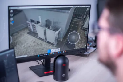 Monitor zobrazuje bodový mrak z 3D skenovania strešnej technológie, vedľa stojí skenovacie zariadenie.