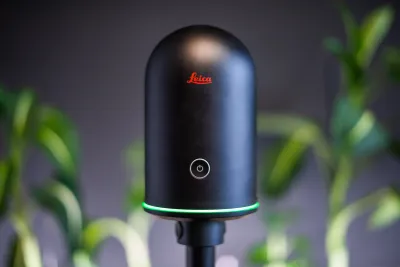 3D skener Leica na statíve v ozelenenom átriu budovy.