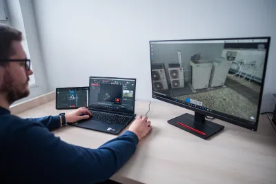 Muž porovnáva 3D sken strešnej technológie na monitore a notebooku.