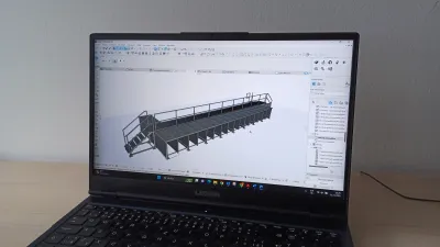 Obrazovka notebooku zobrazuje 3D model kovovej lávky so schodiskom a zábradlím.