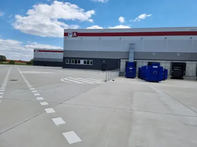 Nakladacia rampa logistickej haly P3 s modrými kontajnermi na odpad pred vratami.