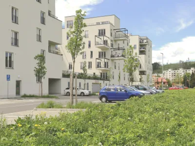 Ulica pred bytovým domom Obytného súboru Kamence s parkujúcimi autami.