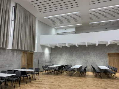 Sála kultúrneho domu s balkónom, akustickými závesmi a pripravenými stolmi.
