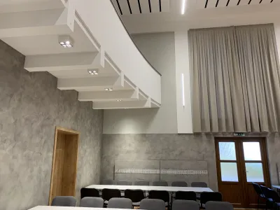 Detail podhľadu balkóna s osvetlením a akustickým závesom v sále kultúrneho domu.