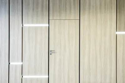 Drevený obklad steny s dverami a LED podsvietením v prednáškovej sále s tlmočníckou kabínou.