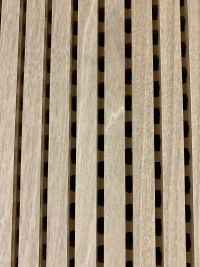 Detailný záber drevených žliabkovaných akustických lamiel na stene prednáškovej sály.