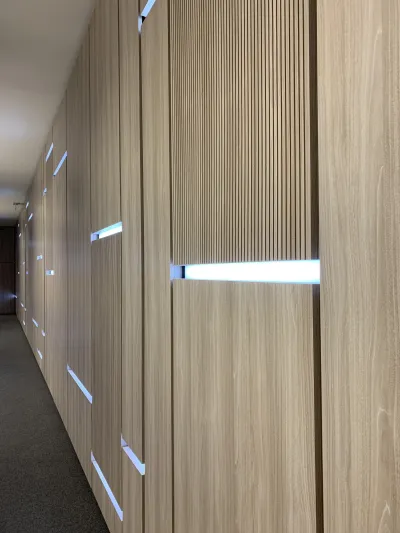 Chodba s dreveným akustickým obkladom stien a LED pásmi pri dverách, prednášková sála s tlmočníckou kabínou.